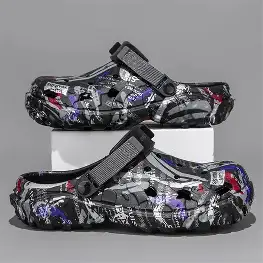 يظهر في الصورة شبشب Crocs رجالي جديد، باللون الرمادي الغامق مع رسومات ملونة (أبيض، بنفسجي، أحمر). يحتوي على فتحات تهوية من الجانبين وشريط خلفي سميك قابل للتعديل.